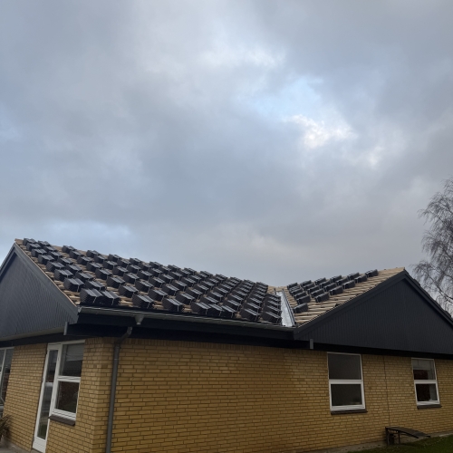 Halvfærdig tagrenovering med tagsten lagt klar til montering – baghave på hus.