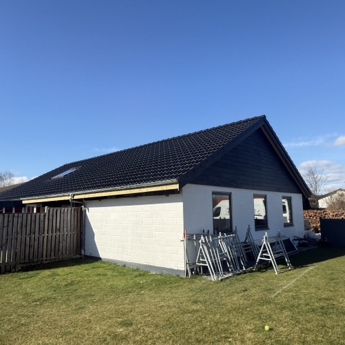 Hus med lys gavl og nyt sort tegltag efter professionel tagrenovering.