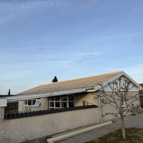 Hus med lys murstensfacade og tagkonstruktion klar til lægning af tagsten.