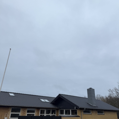 Færdig tagrenovering på villa med mørkt tag og opdateret tagkonstruktion.