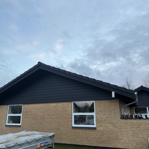 Tagrenovering med ny sort tagbelægning og gavl med sort træbeklædning.
