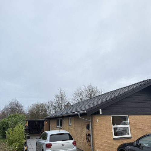 Ny tagrenovering på vinkelhus set fra indkørslen – sort tag med moderne udtryk.