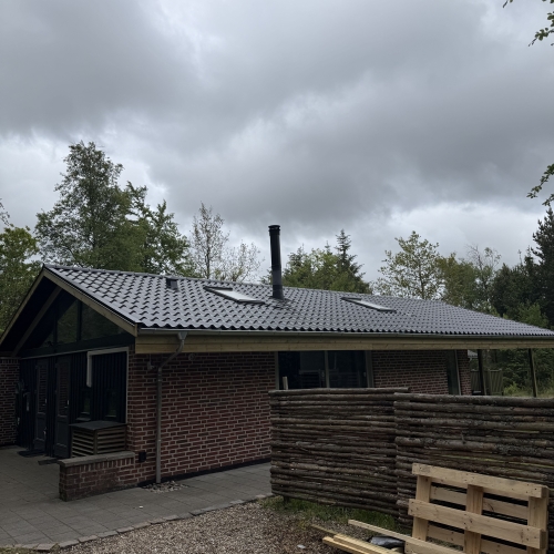 Tagrenovering med sortglaserede tagplader på fritidshus i skovområde