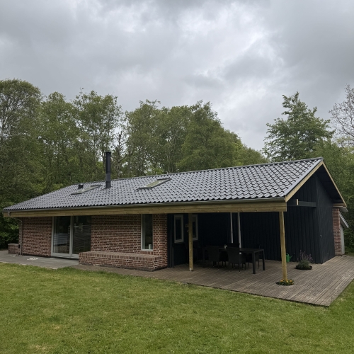 Tagrenovering på klassisk murstenshus med sort tag og overdækket terrasse