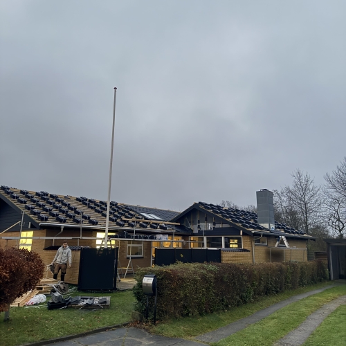 Tagrenovering af enfamiliehus under montage af nye tagsten og stillads.