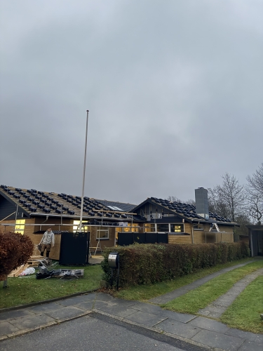 Stor villa under tagrenovering med sort teglstablet på taget og stillads opsat.