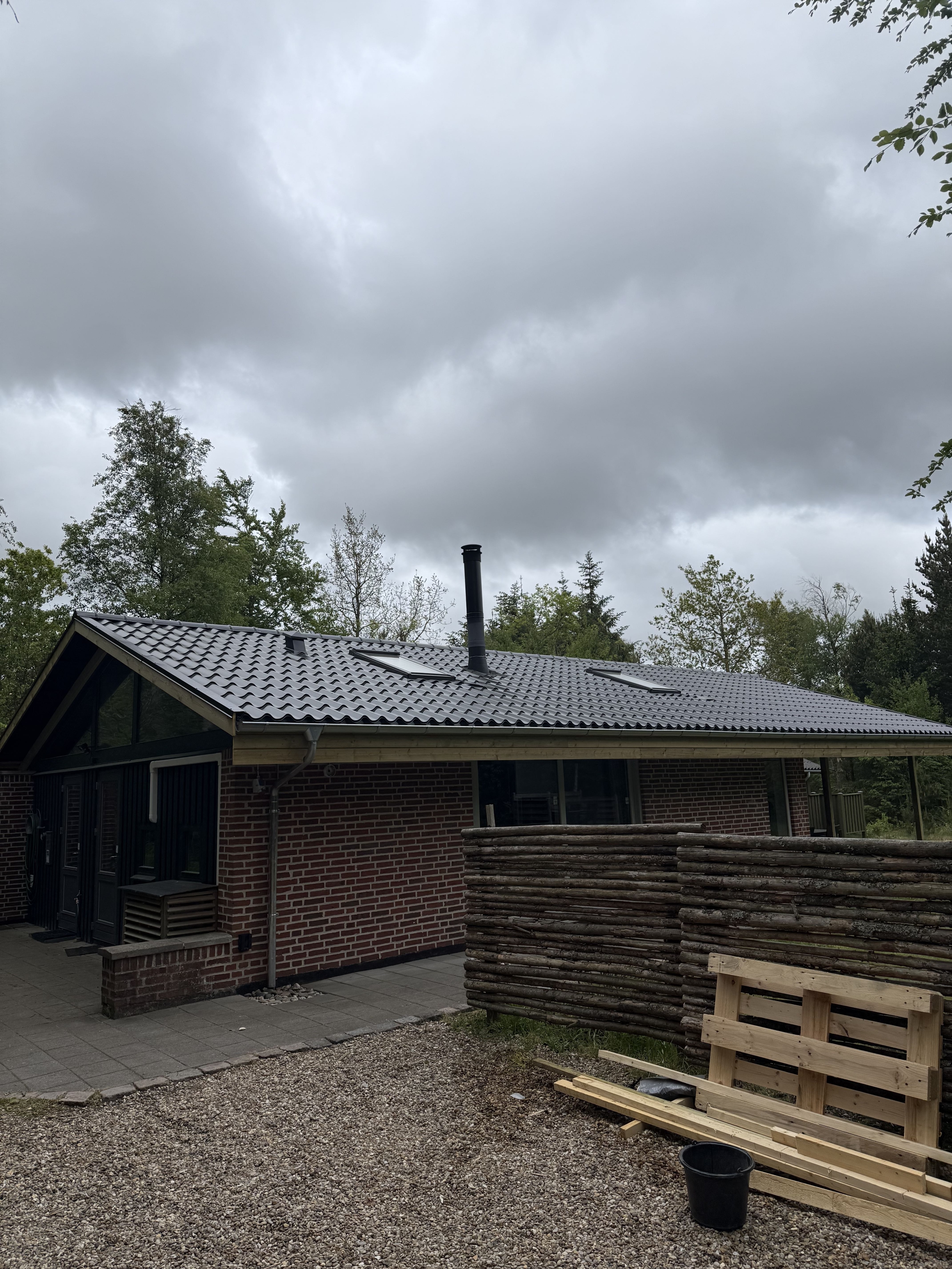 Tagrenovering med sortglaserede tagplader på fritidshus i skovområde